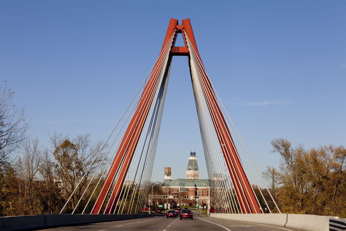 The Robert N. Stewart Bridge in Columbus, Indiana: a red cable-stayed pylon with fans of cables, the county courthouse framed between its legs.